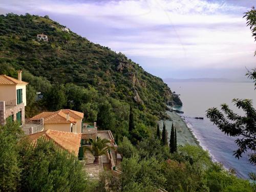 a house on a hill next to a body of water at Kissakas Villas in Leonidion