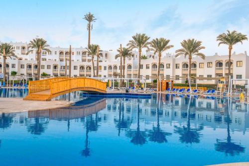 a swimming pool in front of a resort with palm trees at Sunrise Diamond Beach Resort -Grand Select in Sharm El Sheikh