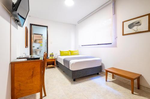 a bedroom with a bed and a desk and a mirror at Ayenda 1502 Principe in Bucaramanga