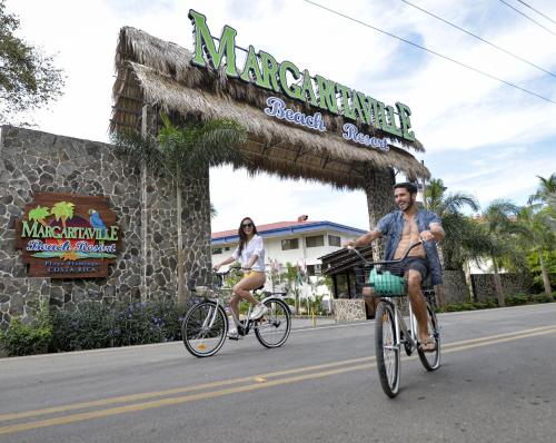a man and woman riding bikes in front of a seafood store at Margaritaville Beach Resort Playa Flamingo in Playa Flamingo