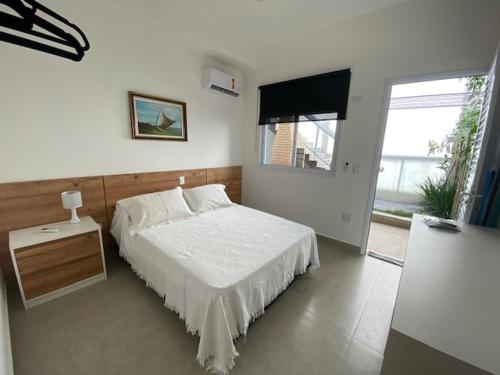 a bedroom with a white bed and a window at Flat Novinho Em Juquehy in Juquei