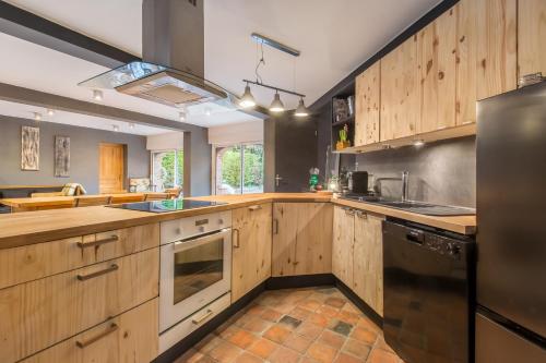 Il comprend une grande cuisine avec des placards en bois et un réfrigérateur. dans l'établissement Le Pigeonnier, maison d'hôtes et Spa, à Croix