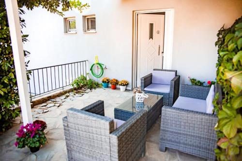 eine Terrasse mit Korbstühlen und einem Glastisch in der Unterkunft Filia Rooms & Apartments in Agio Apóstoloi