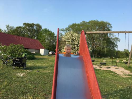 a young boy is riding on a slide at Ljungs Fem Rum in Västergarn