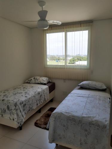 a bedroom with two beds and a window at Apartamento em ótima localização in Torres