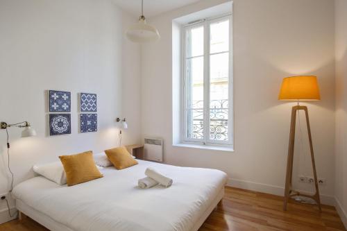 un lit blanc dans une chambre avec une fenêtre dans l'établissement Appartement Cathala - Welkeys, à Marseille