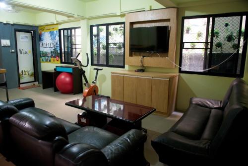 sala de estar con muebles de cuero y TV de pantalla plana en 9 Hostel, en Chiang Mai