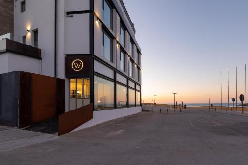a building on the beach with the ocean in the background at Well Hotel & Spa in Maceira