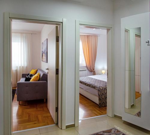 a room with a bed and a couch and a mirror at Apartman Mia in Sremska Mitrovica
