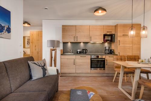a living room and kitchen with a couch and a table at AlpenParks Hotel & Apartment Hochkönig in Mühlbach am Hochkönig