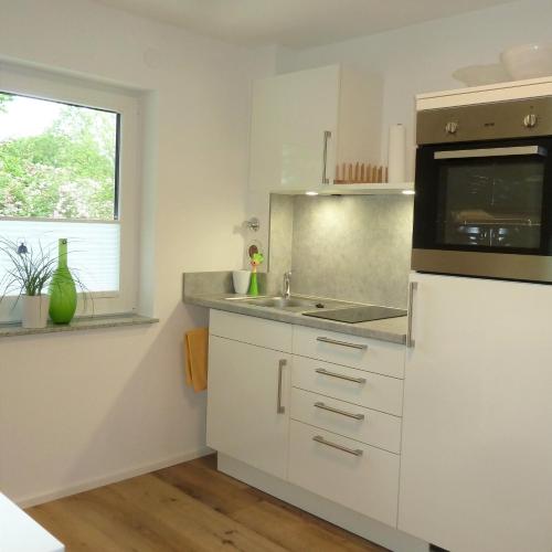 a white kitchen with a sink and a microwave at Wohnen auf Zeit in Weingarten in Weingarten