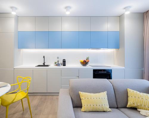 a living room with a couch and a kitchen with blue cabinets at Il Lago - Azur - Cozy Luxurious Smart Home By The Lake in Voluntari