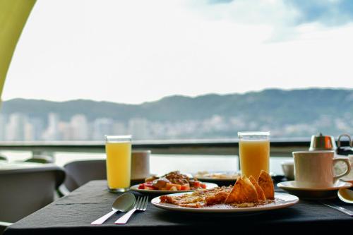 a table with plates of food and two glasses of orange juice at Hotel Las Torres Gemelas Acapulco in Acapulco
