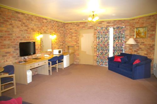 ein Wohnzimmer mit einem blauen Sofa und einem TV in der Unterkunft Pines Country Club Motor Inn in Shepparton