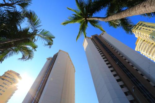 a tall white building with palm trees in the foreground at Hotel Las Torres Gemelas Acapulco in Acapulco