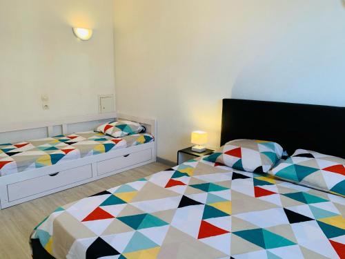 a bedroom with two beds with a colorful comforter at Appartement Vue Mer - 6 personnes in Cerbère
