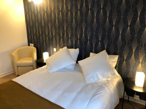 uma cama com lençóis brancos e almofadas num quarto em Le Gîte du Jard em Épernay