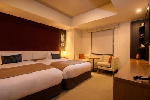 a hotel room with two beds and a chair at Tokyu Stay Ginza in Tokyo