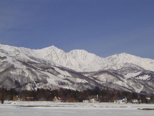 a snow covered mountain range with a town in front at Rosenheim Hakuba in Hakuba
