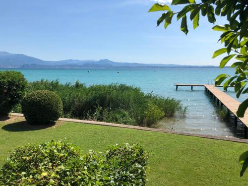 a dock in the water next to a body of water at Lake Front Luxury Apartment in Sirmione
