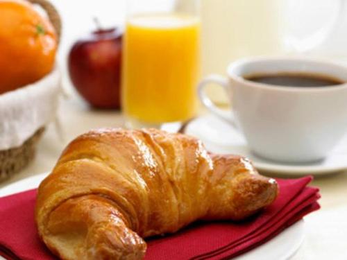 a breakfast plate with a croissant and a cup of orange juice at Pan Tadeusz in Zwierzyniec