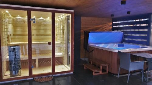 una sauna con una gran ventana y una bañera azul en Erdőalja 11 Apartman, en Nyíregyháza