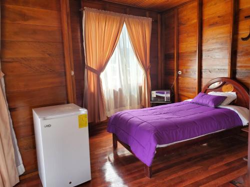 a bedroom with a purple bed and a window at CASA BLANCA HORTENCIA in Sucúa