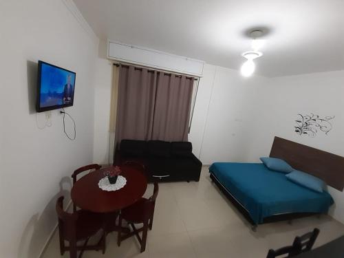a room with a bed and a table and a tv at Kitnet Guarujá Pitangueiras (sem garagem) in Guarujá