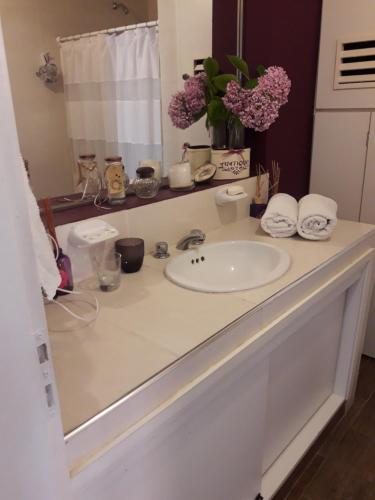 a white bathroom counter with a sink and flowers at La biblioteca in Olavarría
