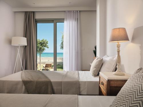 a bedroom with a bed and a view of the beach at Astarte Villas - Onda Beach Villa in Argassi