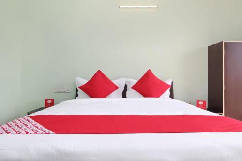 Hotel Nandanvan by Royal Stay في لونافالا: سرير احمر وبيض عليه مخدات حمراء