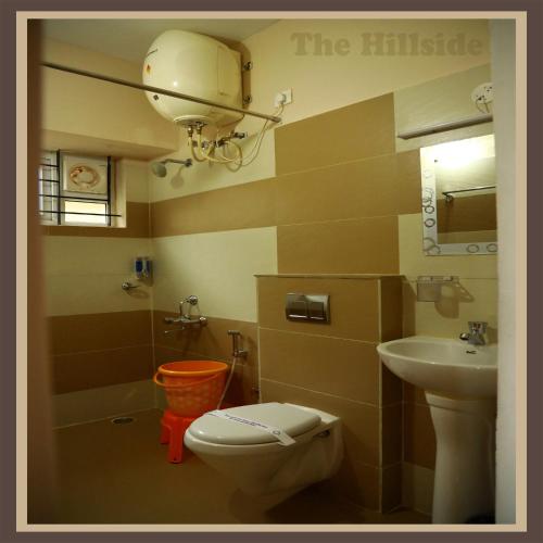 a small bathroom with a toilet and a sink at The Hill Side in Ooty