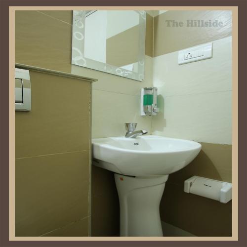 a bathroom with a white sink and a mirror at The Hill Side in Ooty