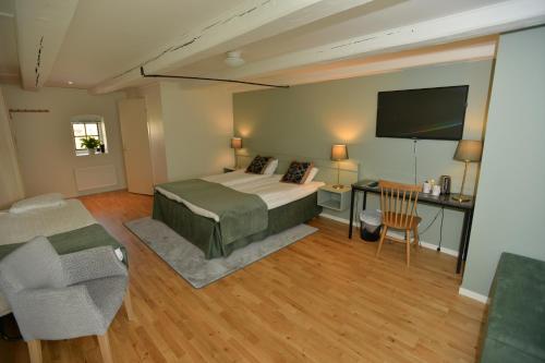 a bedroom with a bed and a desk and a tv at Hotell Magasin 1 in Mörbylånga