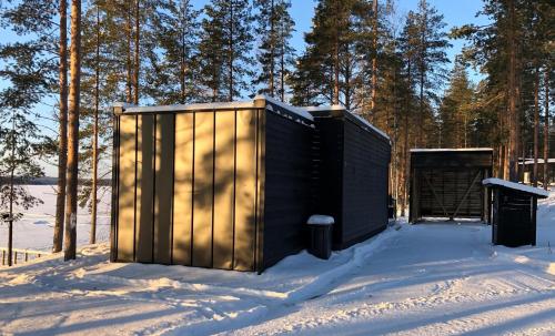 a black shed in the snow with a door at TOP Star Lakeland Viitasaari in Viitasaari