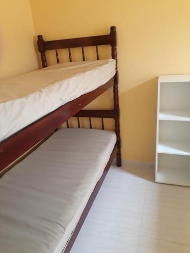a bedroom with two bunk beds and a shelf at Jane Ilha in Ilha Comprida