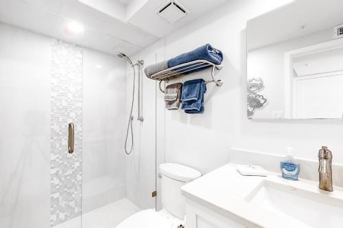 a white bathroom with a shower and a toilet and a sink at Ocean Sands 1105 in St. Pete Beach