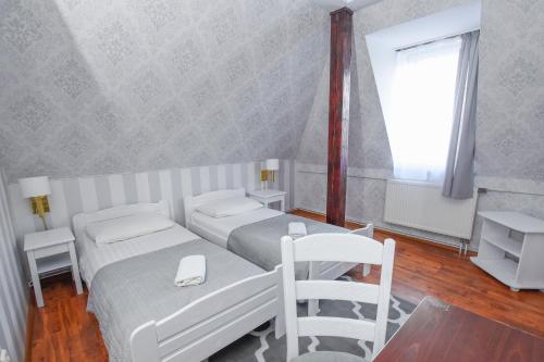 a white bedroom with two beds and a window at Dwór Ostoia in Rymanów