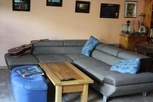 a living room with a couch and a table and a guitar at Au bois de mon coeur in Foameix
