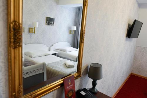 a mirror in a hotel room with two beds at Dwór Ostoia in Rymanów