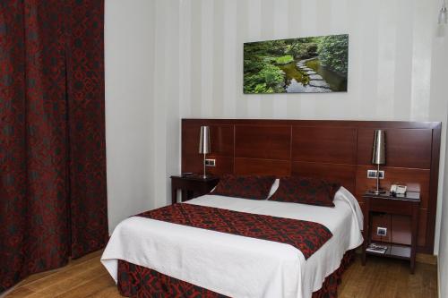 Schlafzimmer mit einem großen Bett mit einem Kopfteil aus Holz in der Unterkunft LB Lebrija Hotel in Lebrija