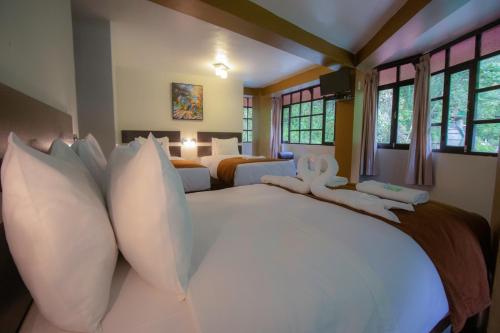 a large bedroom with two beds with white pillows at Samananchis Machupicchu in Machu Picchu