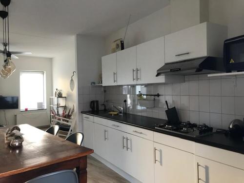a kitchen with white cabinets and a table and a counter at Hart van Lochem in Lochem