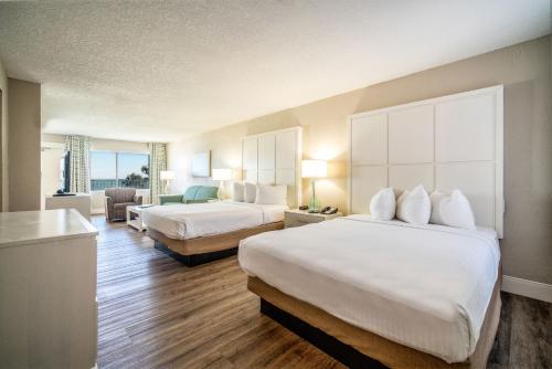 a hotel room with two beds and a living room at Perry's Ocean-Edge Resort in Daytona Beach