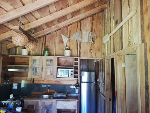 a kitchen with wooden walls and a refrigerator at Wonderful rustic cabin 2, with native logs, on the banks of the Trancura River in Pucón