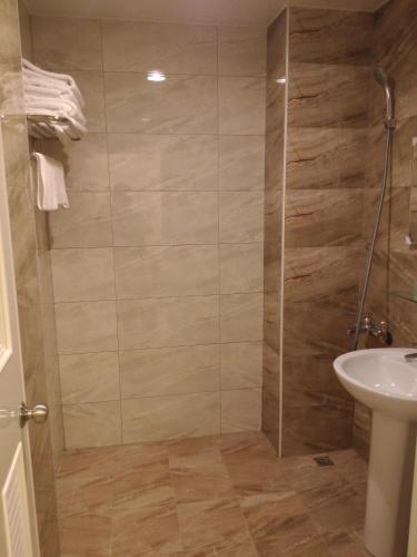 una ducha con una puerta de cristal junto a un lavabo en Tilon Hotel en Pingtung City