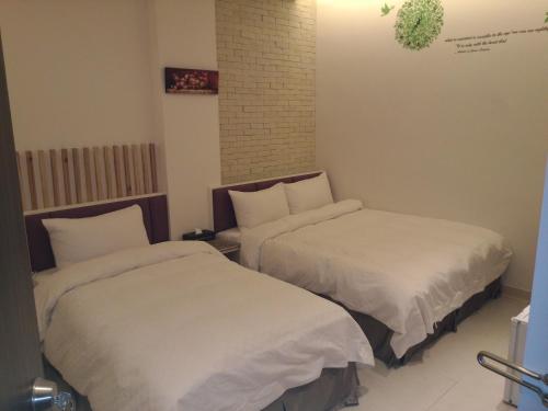 Habitación con 2 camas y sábanas blancas. en Tilon Hotel en Pingtung City