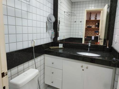 a white bathroom with a sink and a mirror at Ponta Negra Flat 811 in Natal