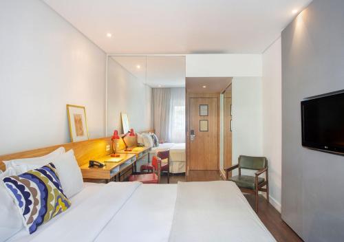 um quarto com uma cama, uma secretária e uma televisão em Ipanema Inn Hotel no Rio de Janeiro
