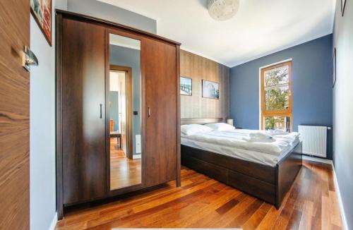 a bedroom with a large bed and a wooden cabinet at Urus Home Sopot in Sopot